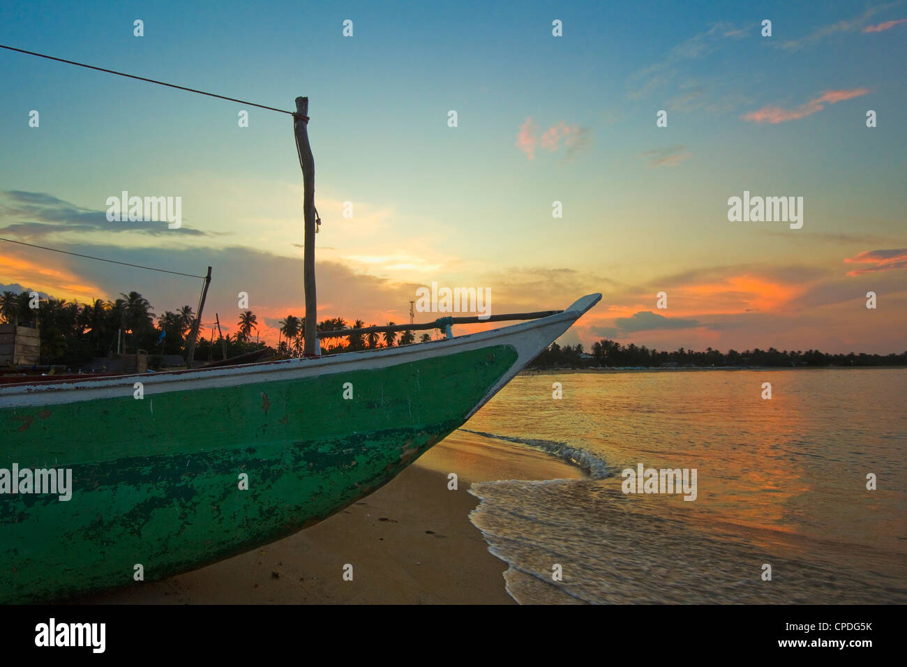 Outrigger bateau au coucher du soleil à cette pêche à la plage et surf, destination touristique populaire d'Arugam Bay, Province Orientale, au Sri Lanka Banque D'Images