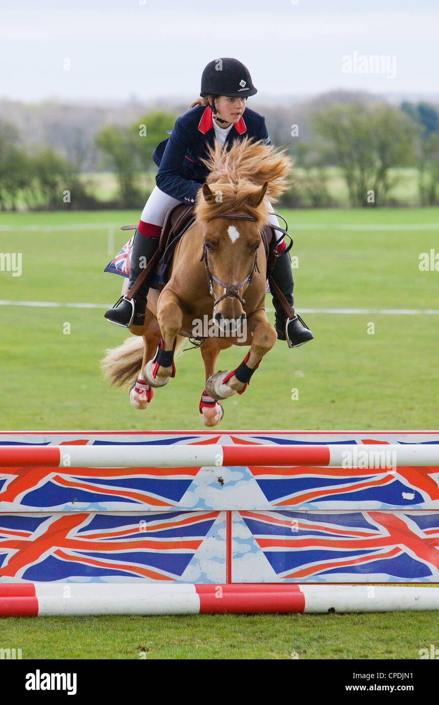 Un cheval et cavalier en compétition de saut d'un événement tenu à l'extérieur, sur un terrain de sport en Angleterre Banque D'Images