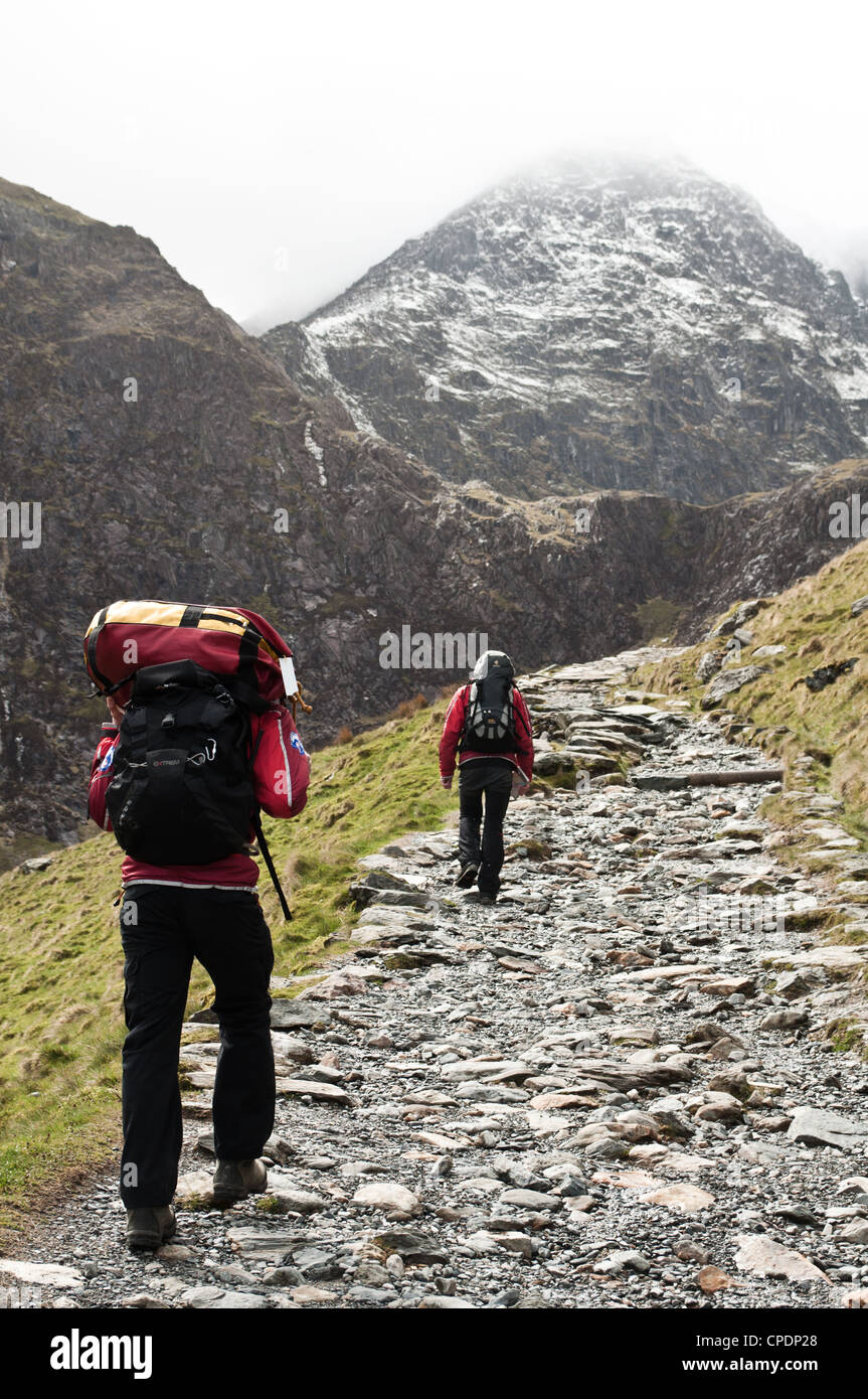 Les membres de l'équipe de secours en montagne Aberglaslyn partez à la recherche de blessés Walker sur le mont Snowdon, avec de lourdes charges de kit de secours Banque D'Images
