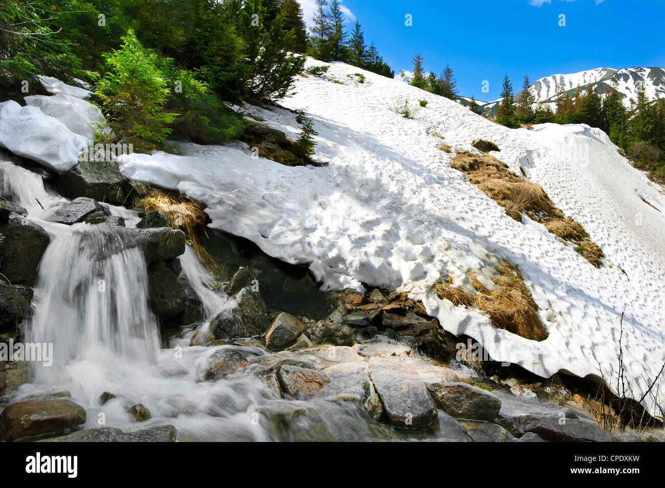 Paysage de montagne avec de la neige de printemps et chute d'eau plus de ciel bleu Banque D'Images