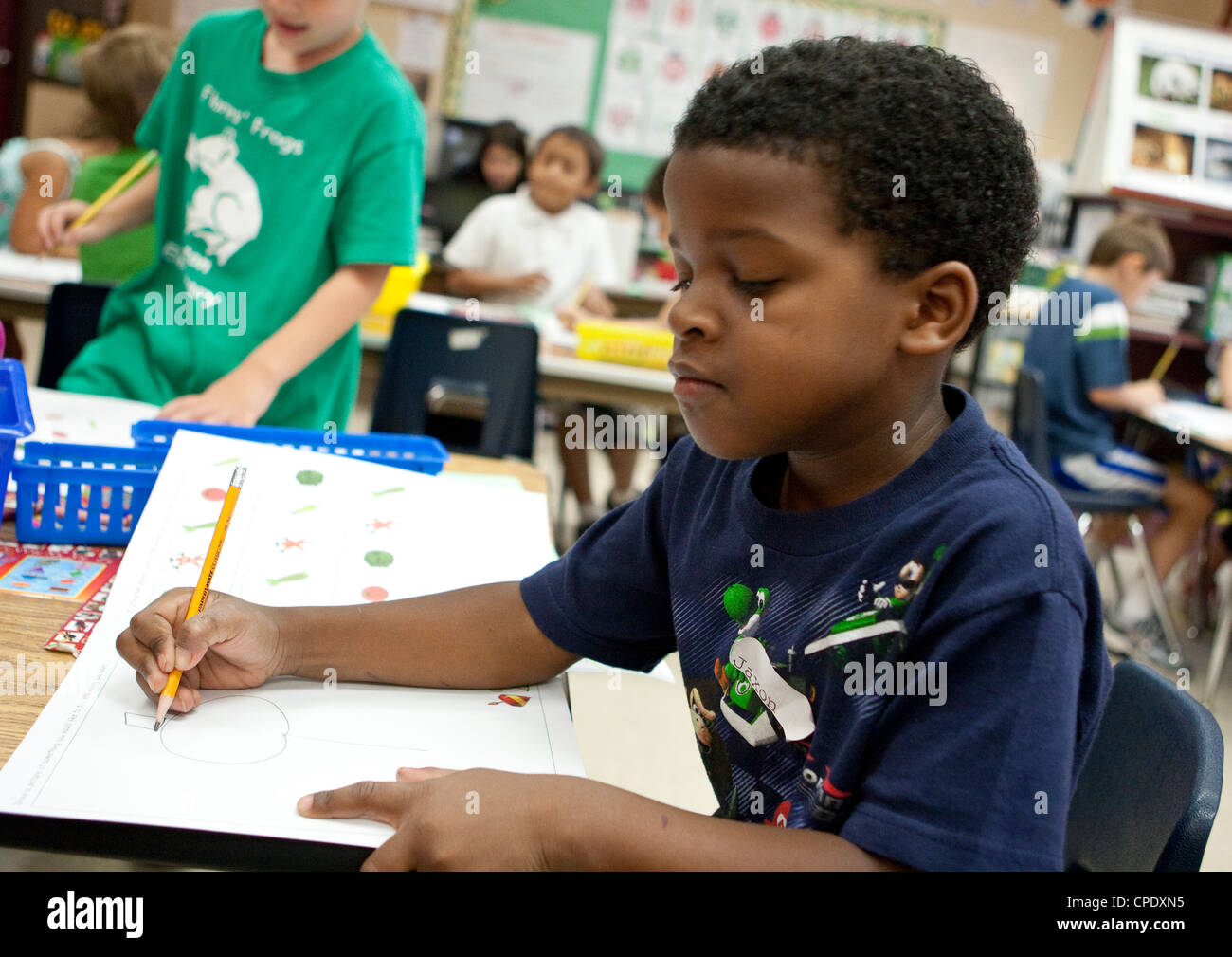 Les hommes afro-américains de la maternelle élève travaille à son bureau pendant la classe à l'école élémentaire publique du Texas Banque D'Images