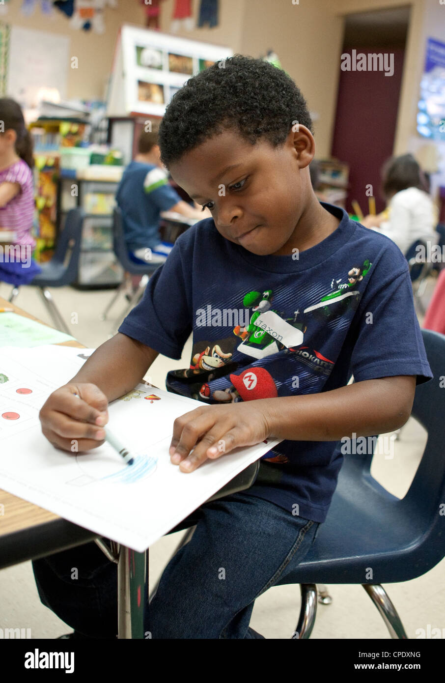 Les hommes afro-américains de la maternelle élève travaille à son bureau pendant la classe à l'école élémentaire publique du Texas Banque D'Images