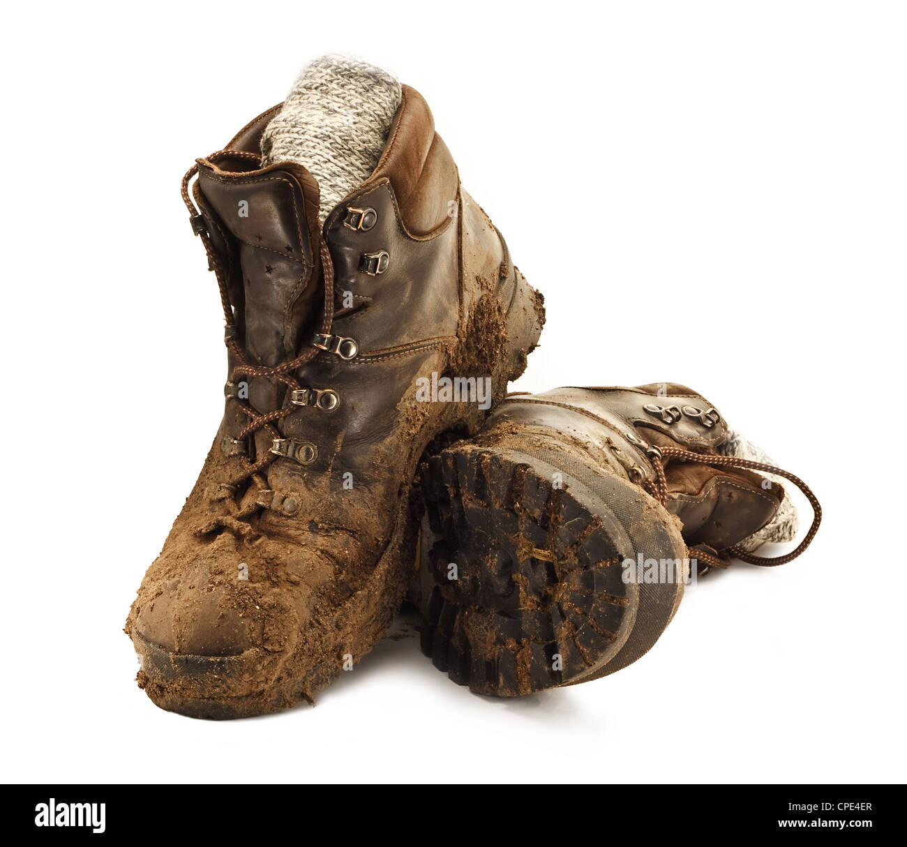Paire de chaussures de randonnée marron sale dans la boue agglutinée isolé sur un fond blanc Banque D'Images