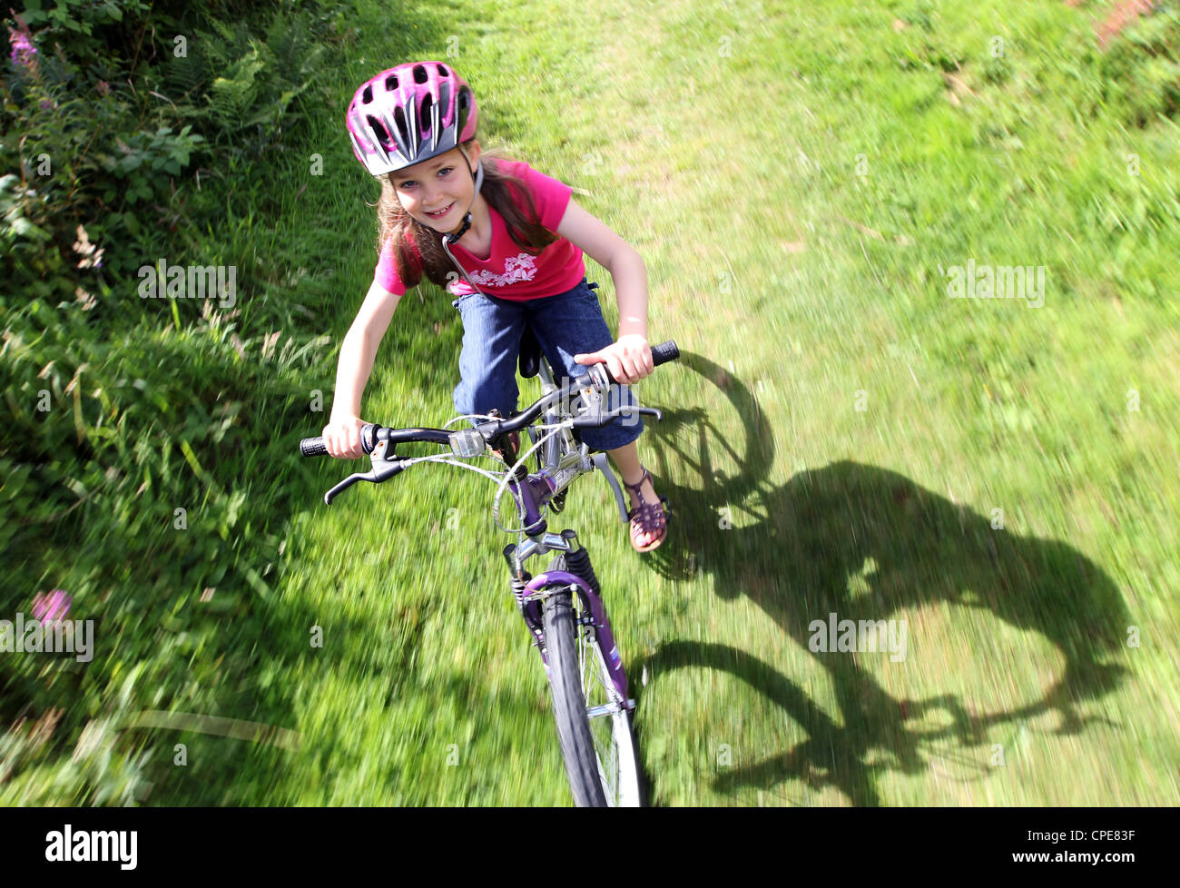 Une fille de 8 ans, bénéficie d'une promenade en vélo à travers la campagne sur une journée ensoleillée. Banque D'Images