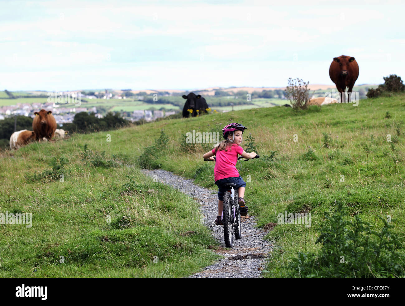 Une fille de 8 ans, bénéficie d'une promenade en vélo à travers la campagne sur une journée ensoleillée. Banque D'Images