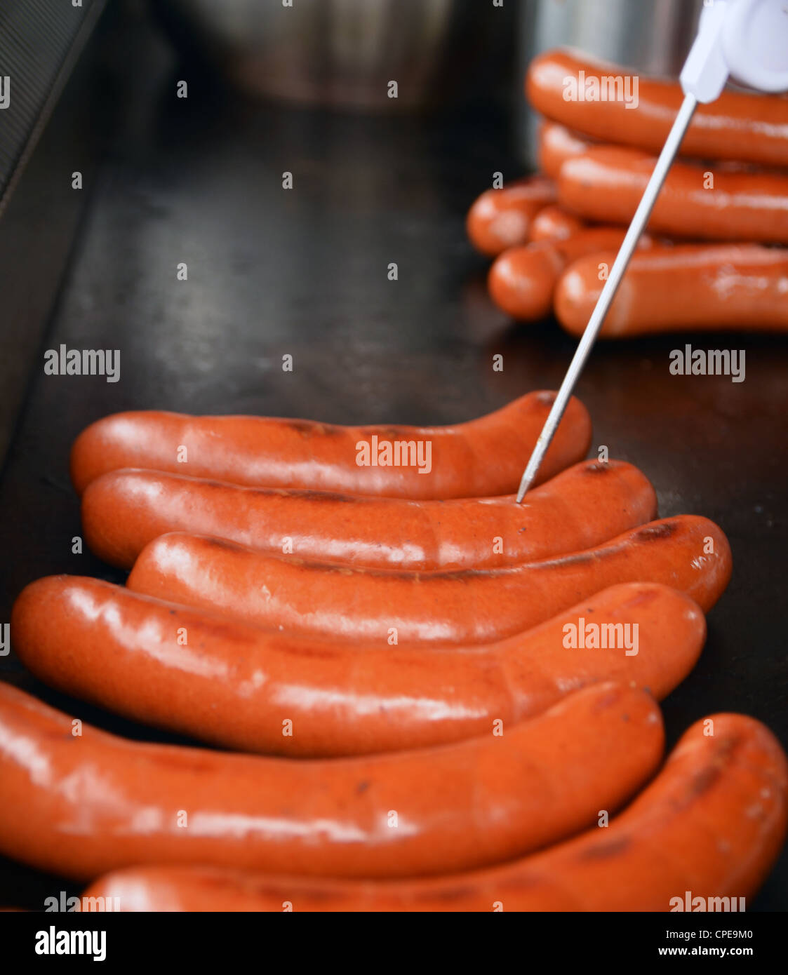 Prendre la température de saucisses à hot-dog avec thermomètre à viande sur plaque Banque D'Images