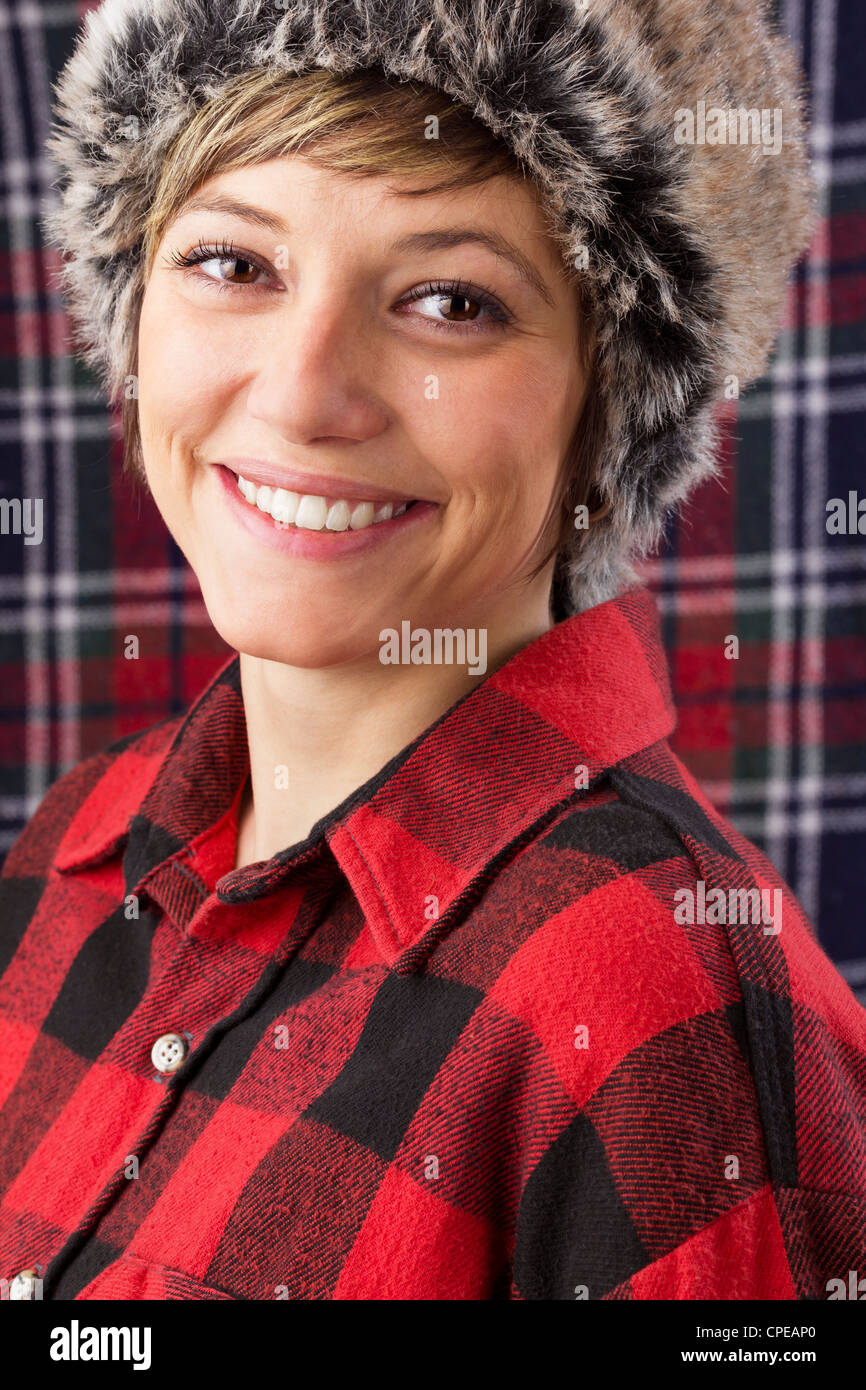 Belle jeune femme porter du rouge et noir et chemise de bûcheron vérifié fur hat. Studio shot comme portrait. Banque D'Images