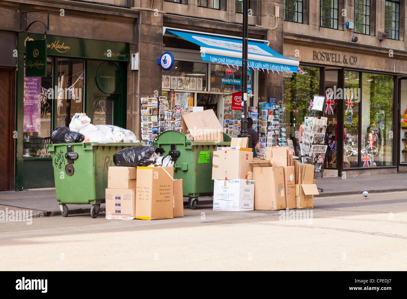 Deux sauts et plusieurs cartons de déchets ou des déchets en attente sur le trottoir pour la collecte, dans Broad Street, Oxford, Angleterre. Banque D'Images