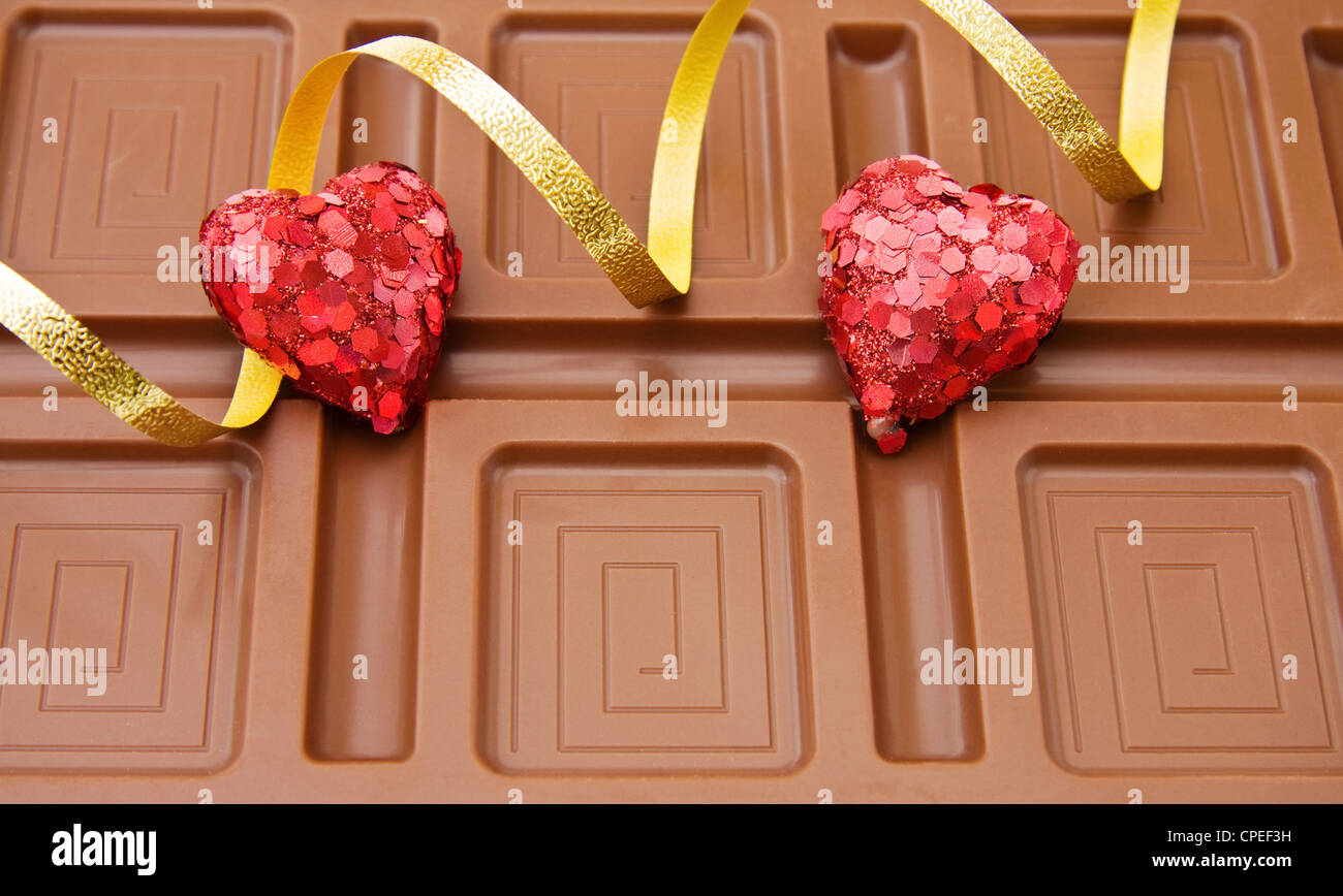 Grande barre de chocolat belge avec des coeurs et des rubans d'or pour la célébration d'une journée spéciale. Banque D'Images