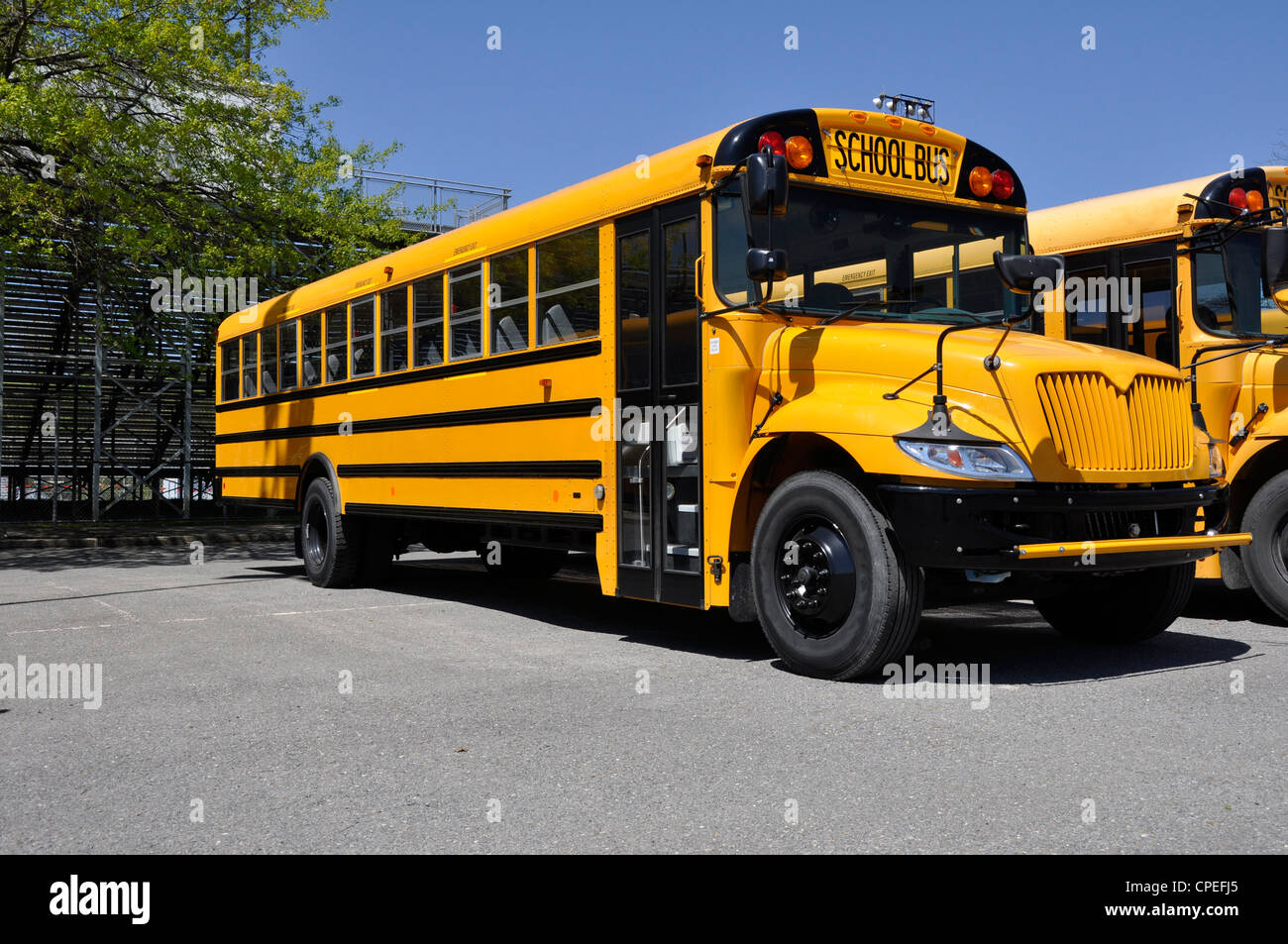 Un autobus scolaire jaune garé par un parking macadam Banque D'Images