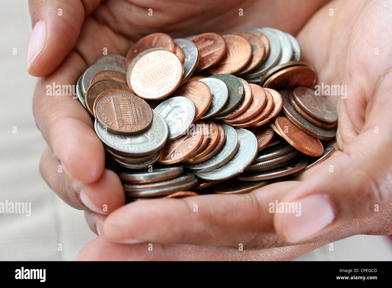 Pile de pièces de monnaie dans une main de femme assise Banque D'Images