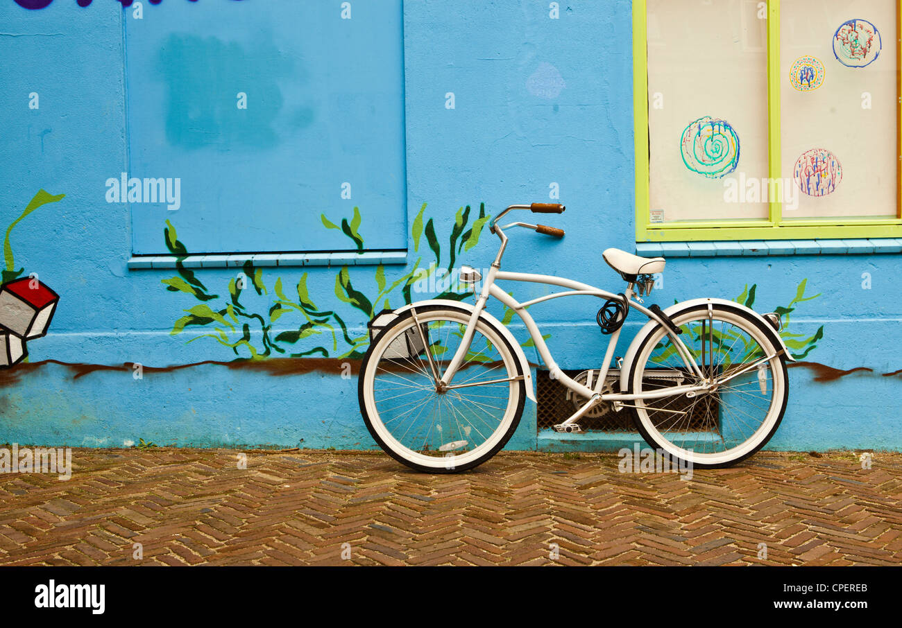 Un vieux vélo blanc appuyé contre un mur bleu Banque D'Images