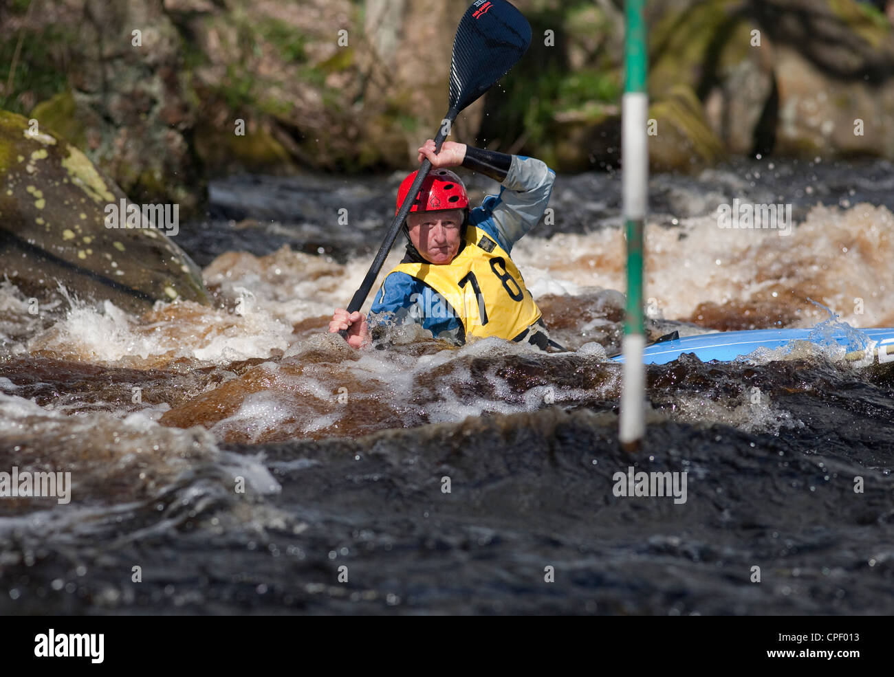 Les hommes d'âge moyen ; concurrent dans un kayak de slalom, la concurrence à la Washburn Valley, North Yorkshire Avril 2012 Banque D'Images