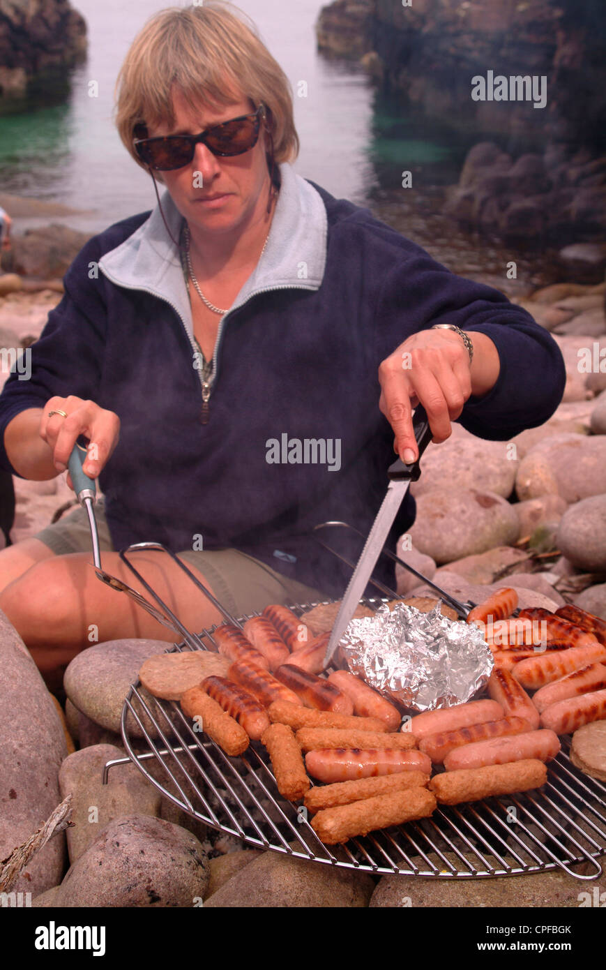 Woman barbecuing sausages sur la plage Banque D'Images