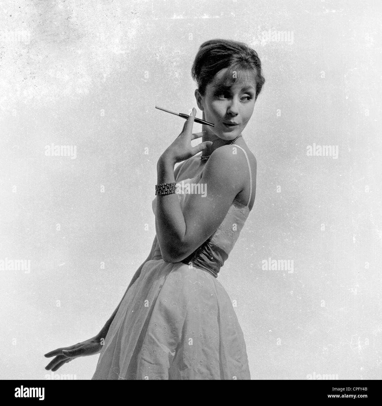 Années 1960. Une dame fumer une cigarette à l'aide d'un porte-cigarette. Banque D'Images