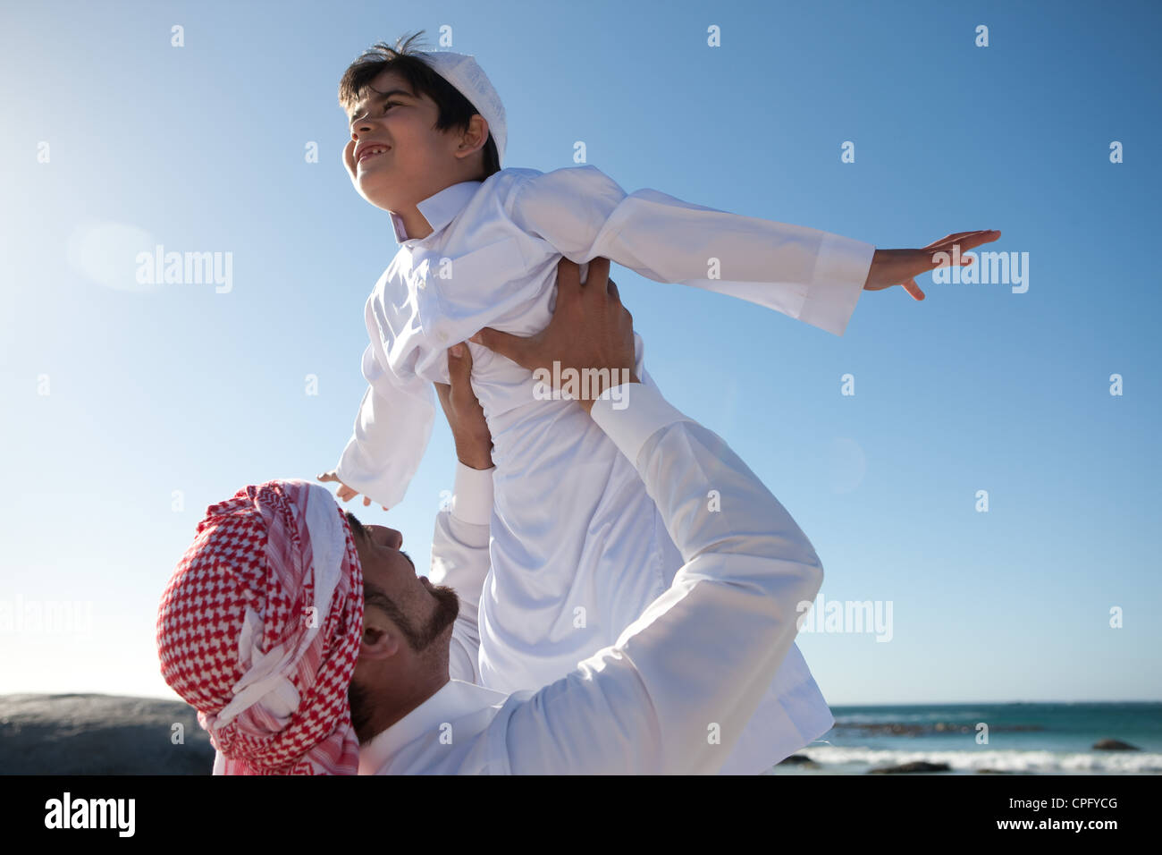 Père arabe de lever son fils sur beach boy, bras levés. Banque D'Images