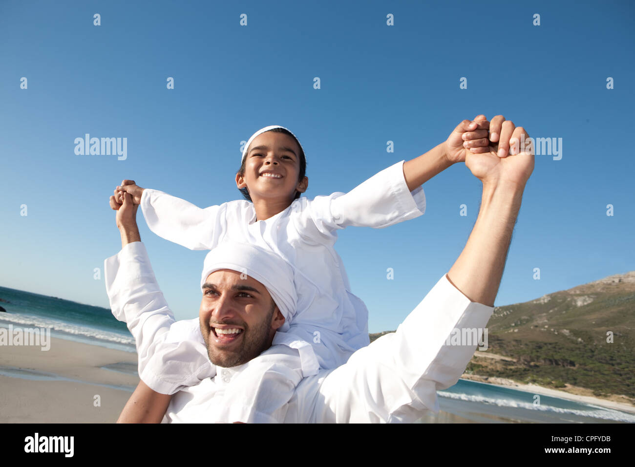 Père arabe portant son fils sur les épaules à la plage, en souriant Photo Stock Alamy