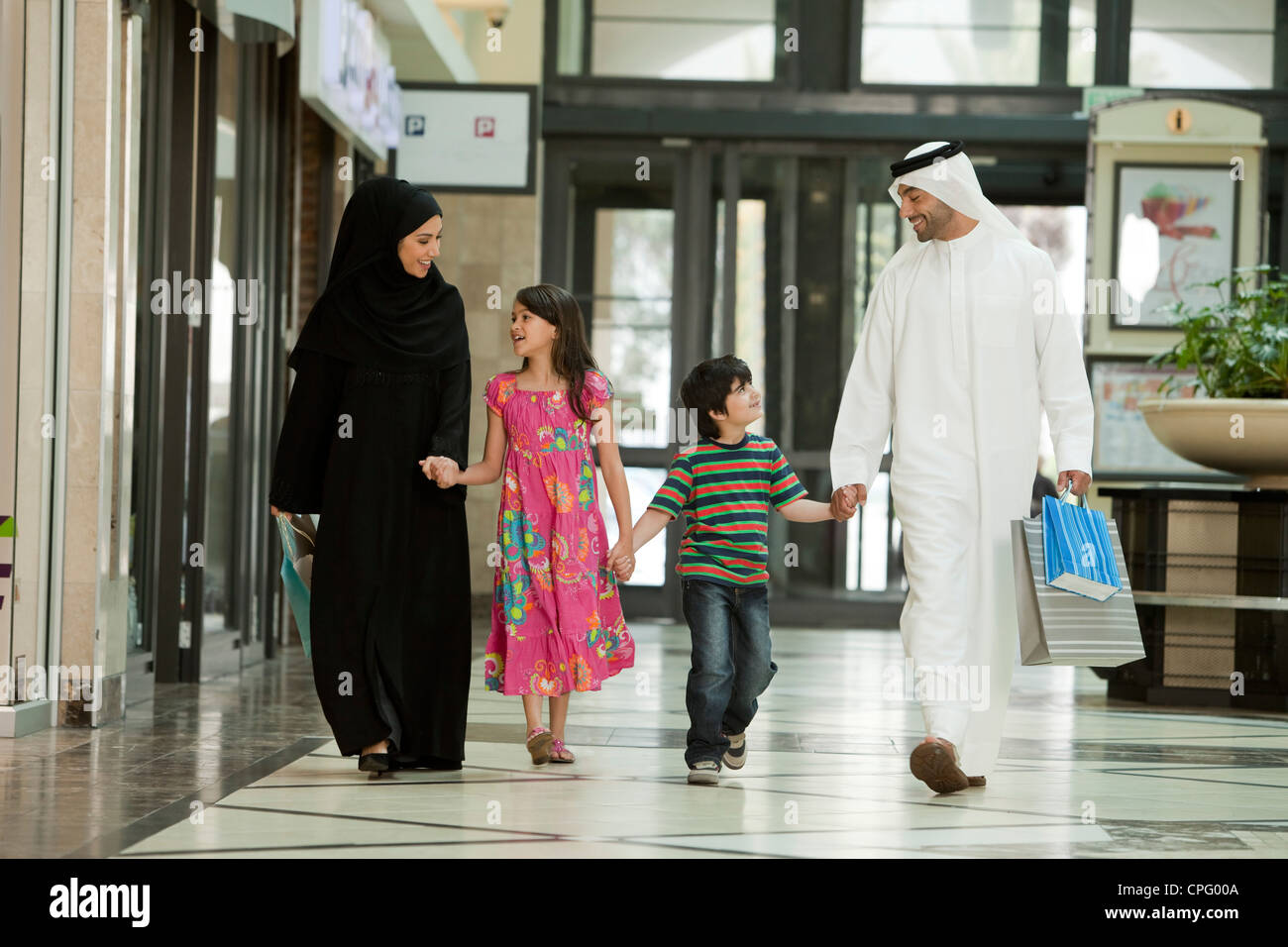 Famille arabe tenant la main tout en marchant dans le centre commercial. Banque D'Images