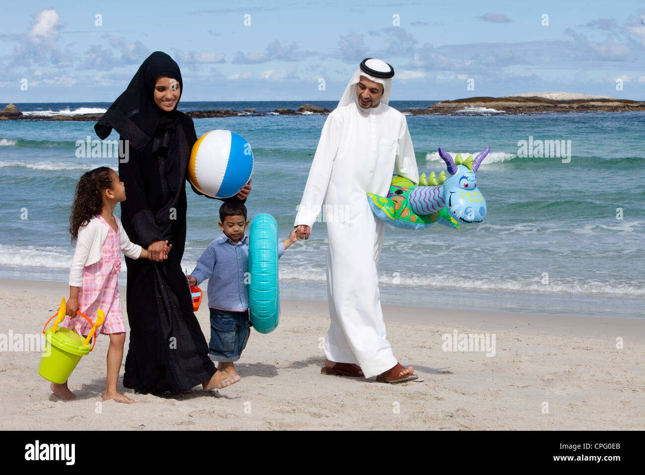 Famille arabe tenant la main en marchant sur la plage. Banque D'Images