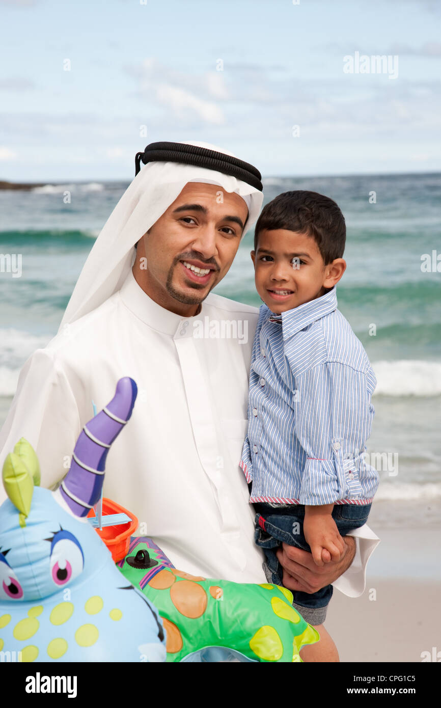 Père et fils arabe à la plage, en souriant. Banque D'Images