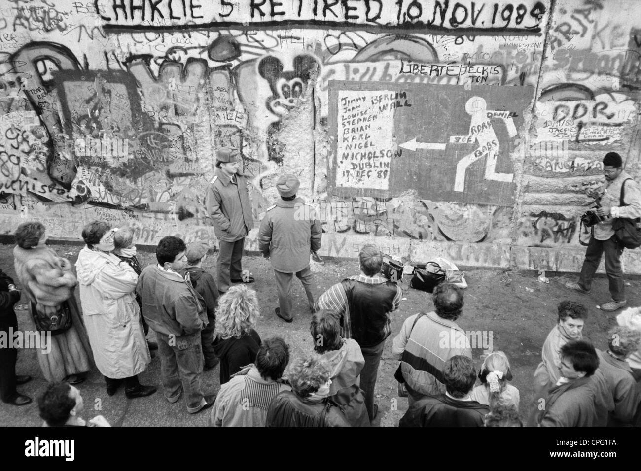 Les gardes-frontières de l'est à Checkpoint Charlie à la recherche à un graffiti sur le mur de Berlin, Allemagne dévastée Banque D'Images