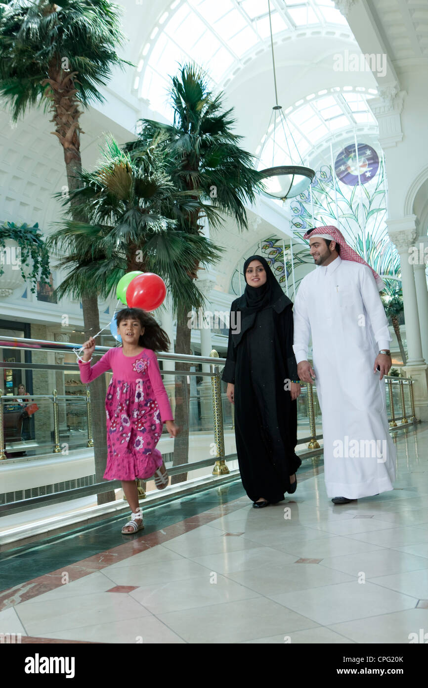 Dans la famille arabe shopping mall, fille courir avec des ballons. Banque D'Images