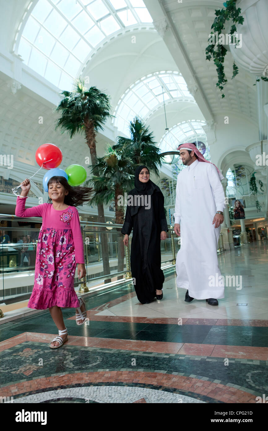Dans la famille arabe shopping mall, fille courir avec des ballons. Banque D'Images