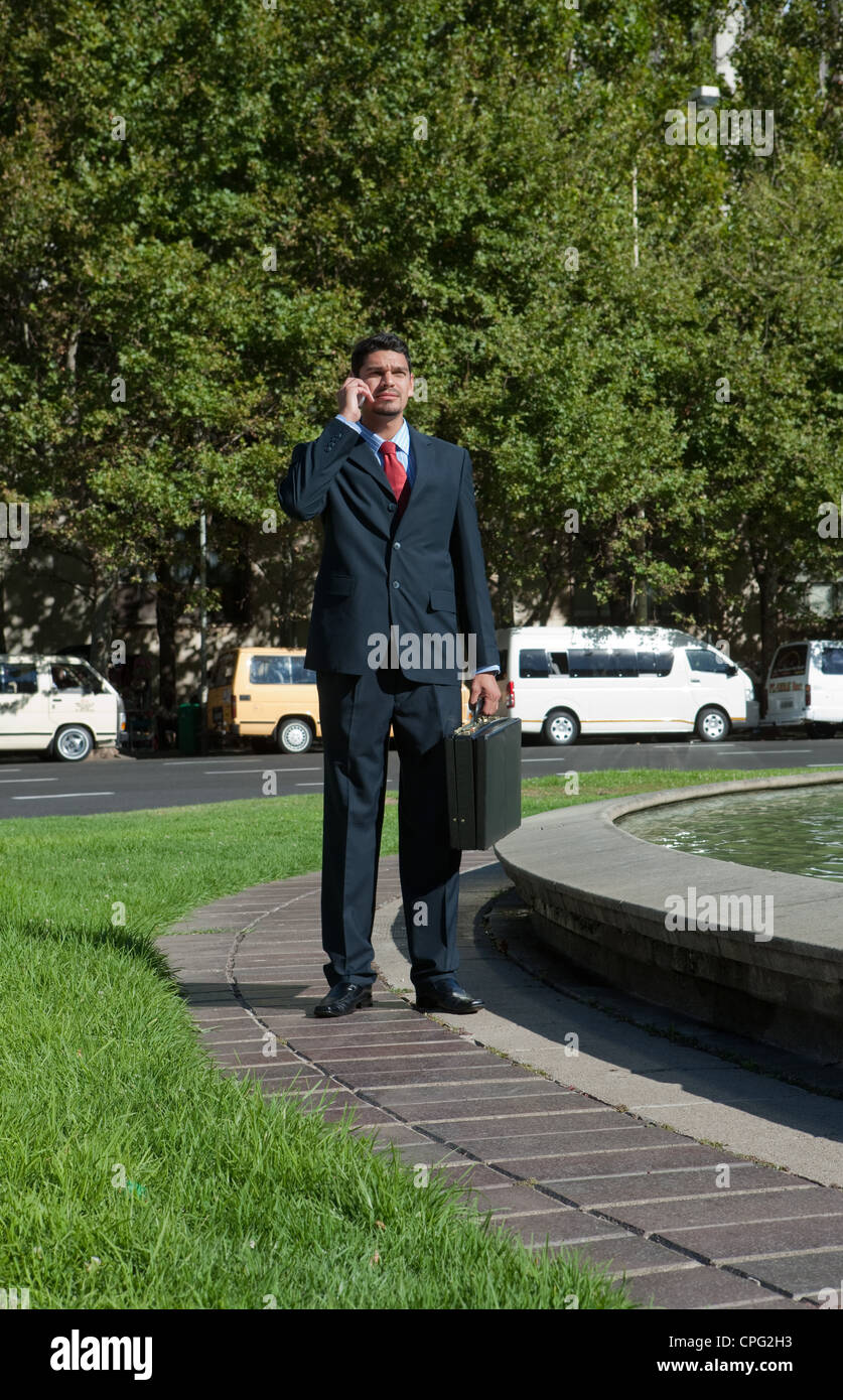 Businessman with mobile phone, debout près de la rue. Banque D'Images