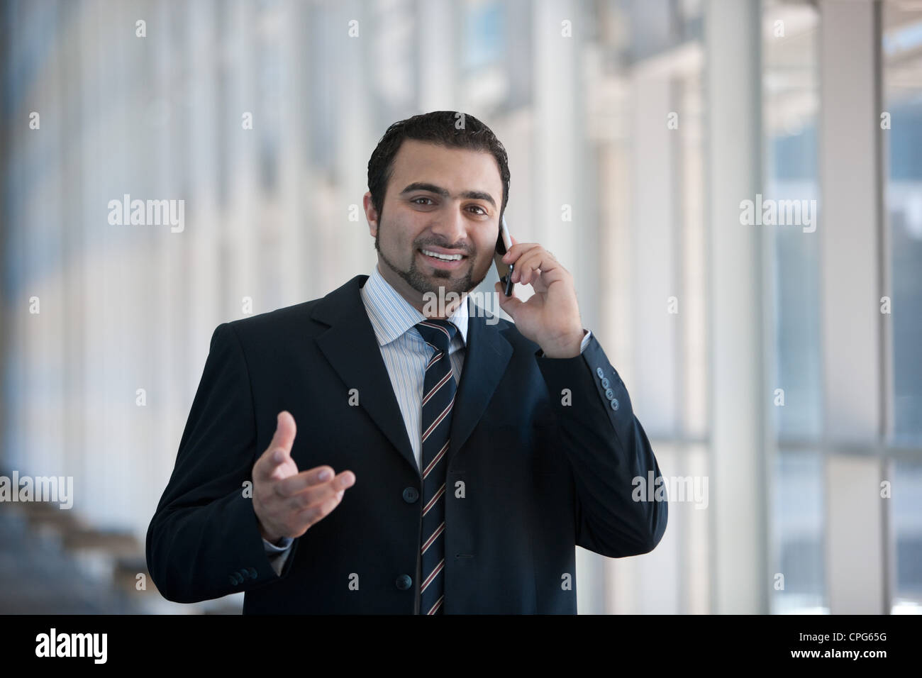 Businessman using mobile phone, par le bureau permanent de couloir. Banque D'Images