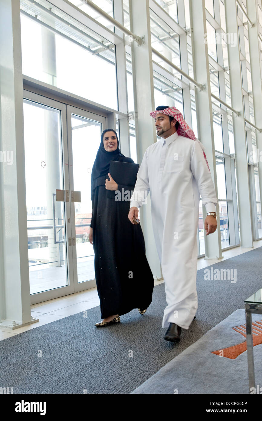 Businessman and businesswoman arabes à parler tout en marchant dans le couloir. bureau Banque D'Images