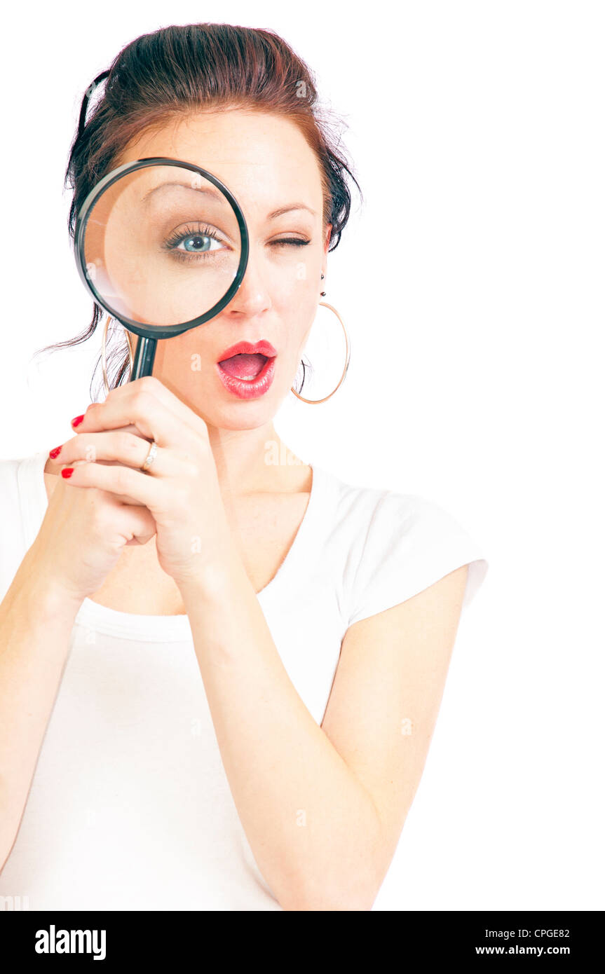 Jolie jeune femme à travers une loupe isolé sur un fond blanc. Banque D'Images