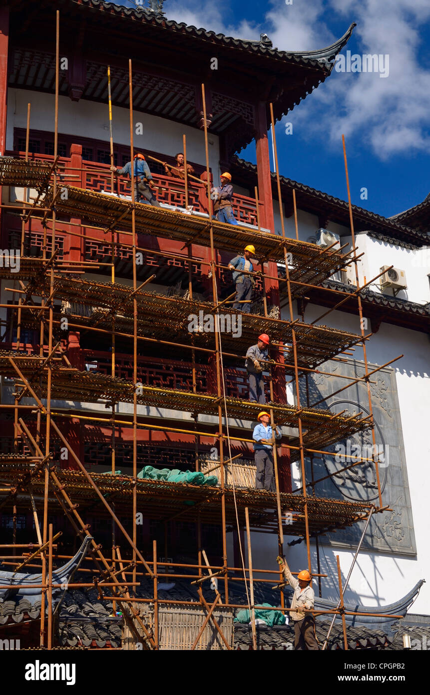 Les travailleurs de la construction sur des échafaudages de barres de levage rénover un immeuble dans le vieux Shanghai République populaire de Chine Banque D'Images