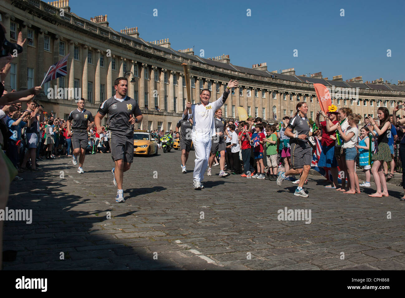 Christopher Phillips, 37, (centre) porte le flambeau olympique autour du Royal Crescent à Bath, Somerset, UK,le mardi 22 mai Banque D'Images