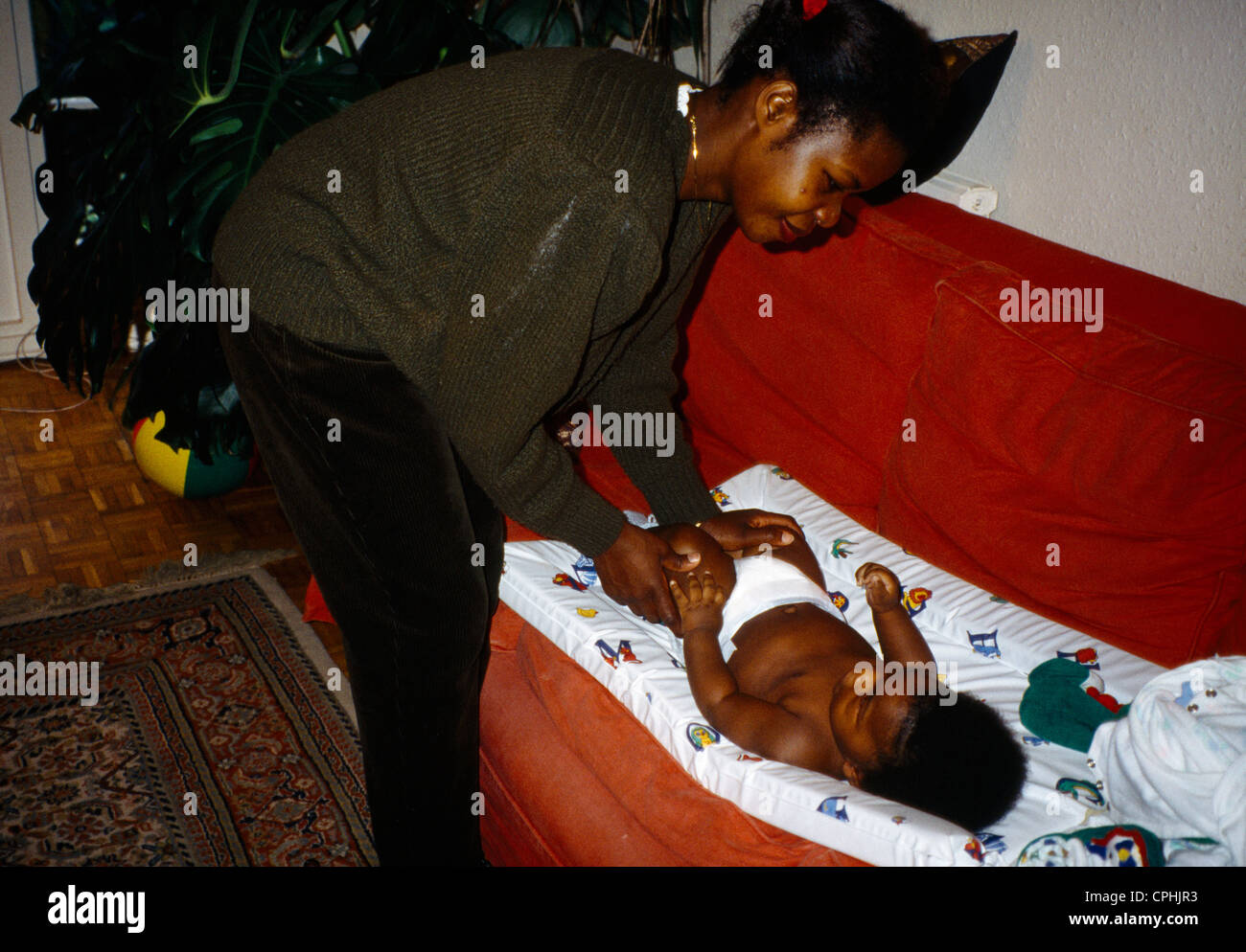 Mère Afro Antillais et Nappy change bébé sur le matelas à langer Banque D'Images