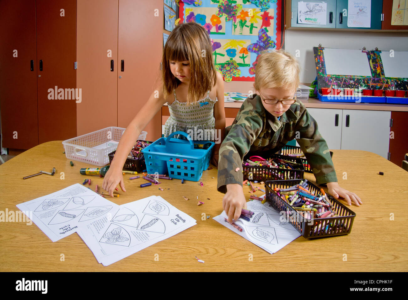 Les enfants de maternelle San Clemente CA recueillir et organiser une table pleine d'objets de classe y compris des crayons et des feuilles de Banque D'Images