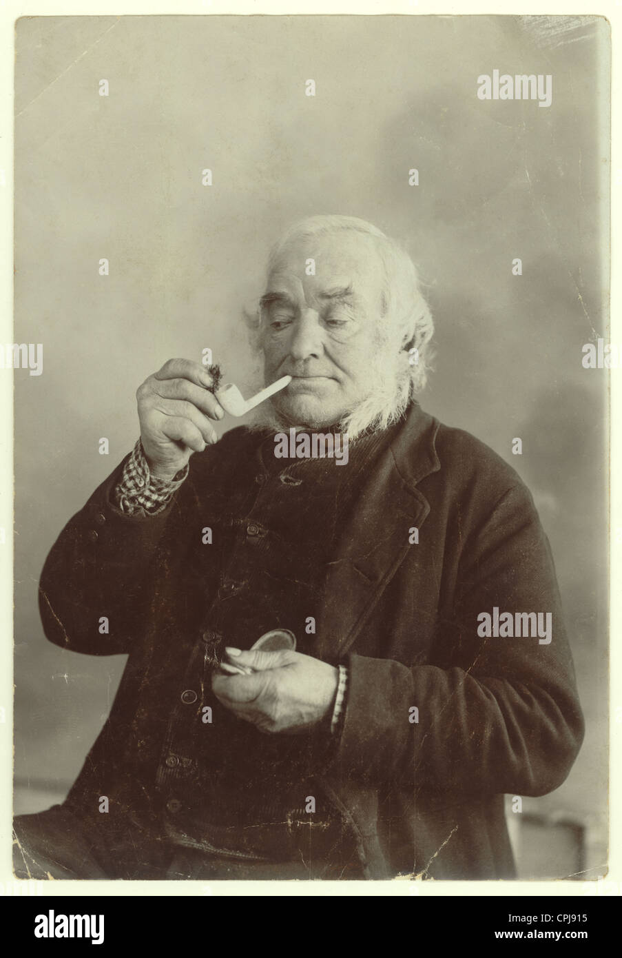 Portrait d'un ancien homme victorien mettant du tabac dans un tube d'argile d'un studio à Liskeard, Cornwall, Angleterre, Royaume-Uni Banque D'Images
