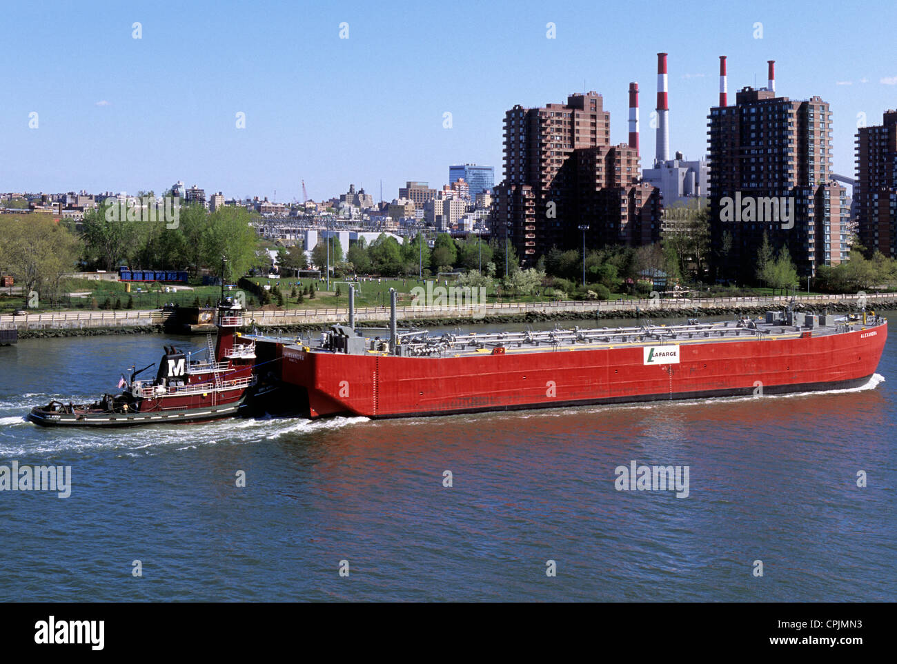 Remorqueur ou remorqueur et chaland de pétrole East River New York City. Bâtiments et Con Edison fument sur Roosevelt Island dans le Queens USA tarifs sur le pétrole Banque D'Images