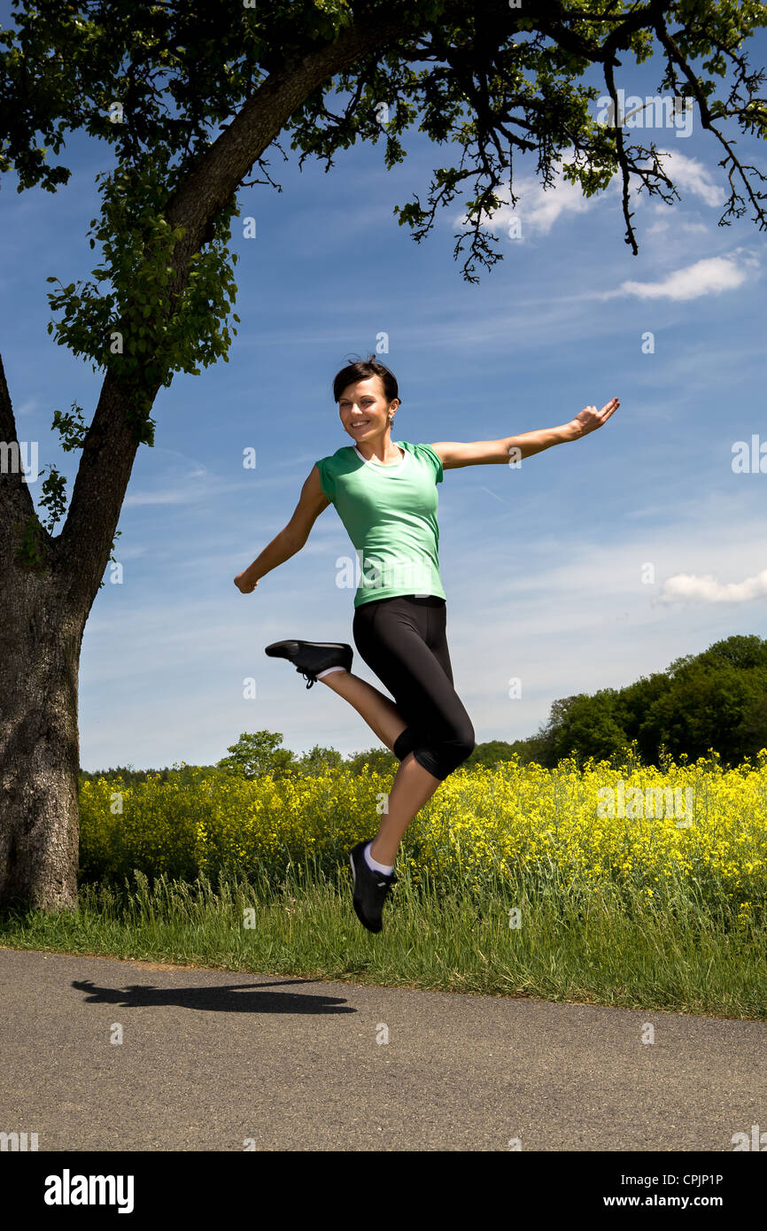 Une jeune femme sautant en face de paysage rural Banque D'Images