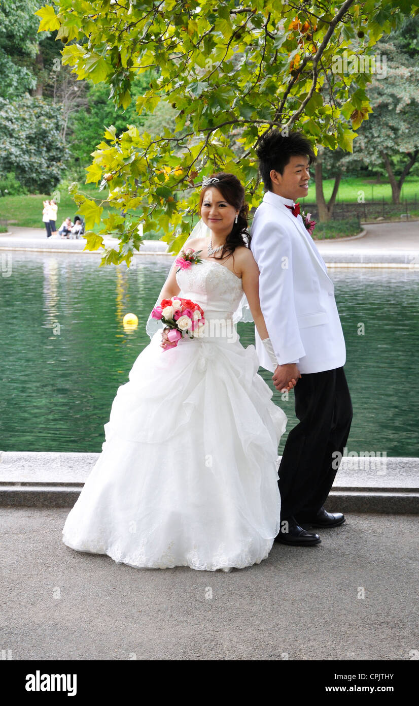Un jeune couple asiatique pose pour la photo de leur mariage près d'un étang dans Central Park, New York City Banque D'Images