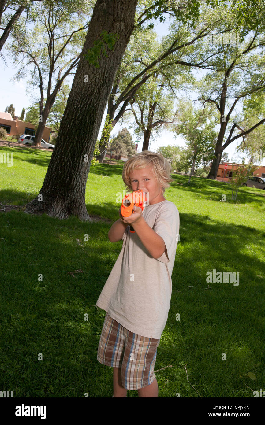 Garçon de dix ans tenant un pistolet nerf en plastique dans un parc, a fait à huis clos. Banque D'Images
