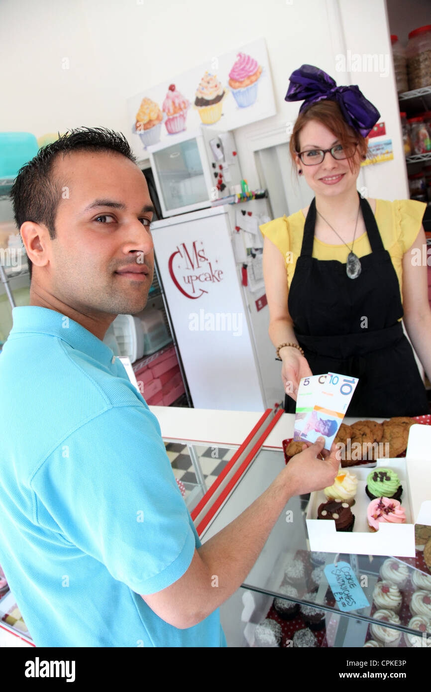 Un homme paie pour cupcakes avec la Brixton Pound, une monnaie locale qui longe Sterling afin de promouvoir les commerces locaux Banque D'Images