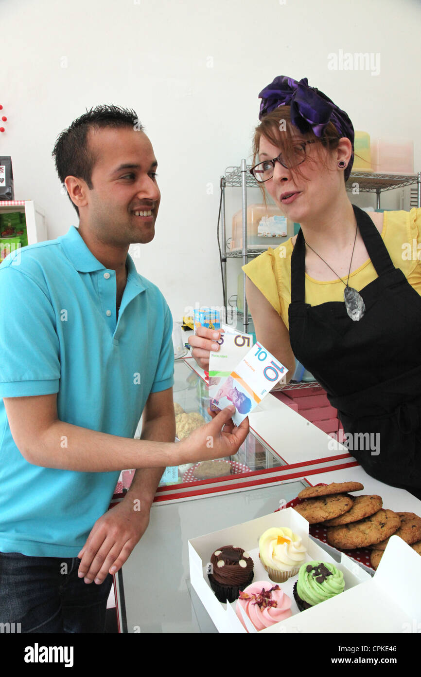 Un homme paie pour cupcakes avec la Brixton Pound, une monnaie locale qui longe Sterling afin de promouvoir les commerces locaux Banque D'Images
