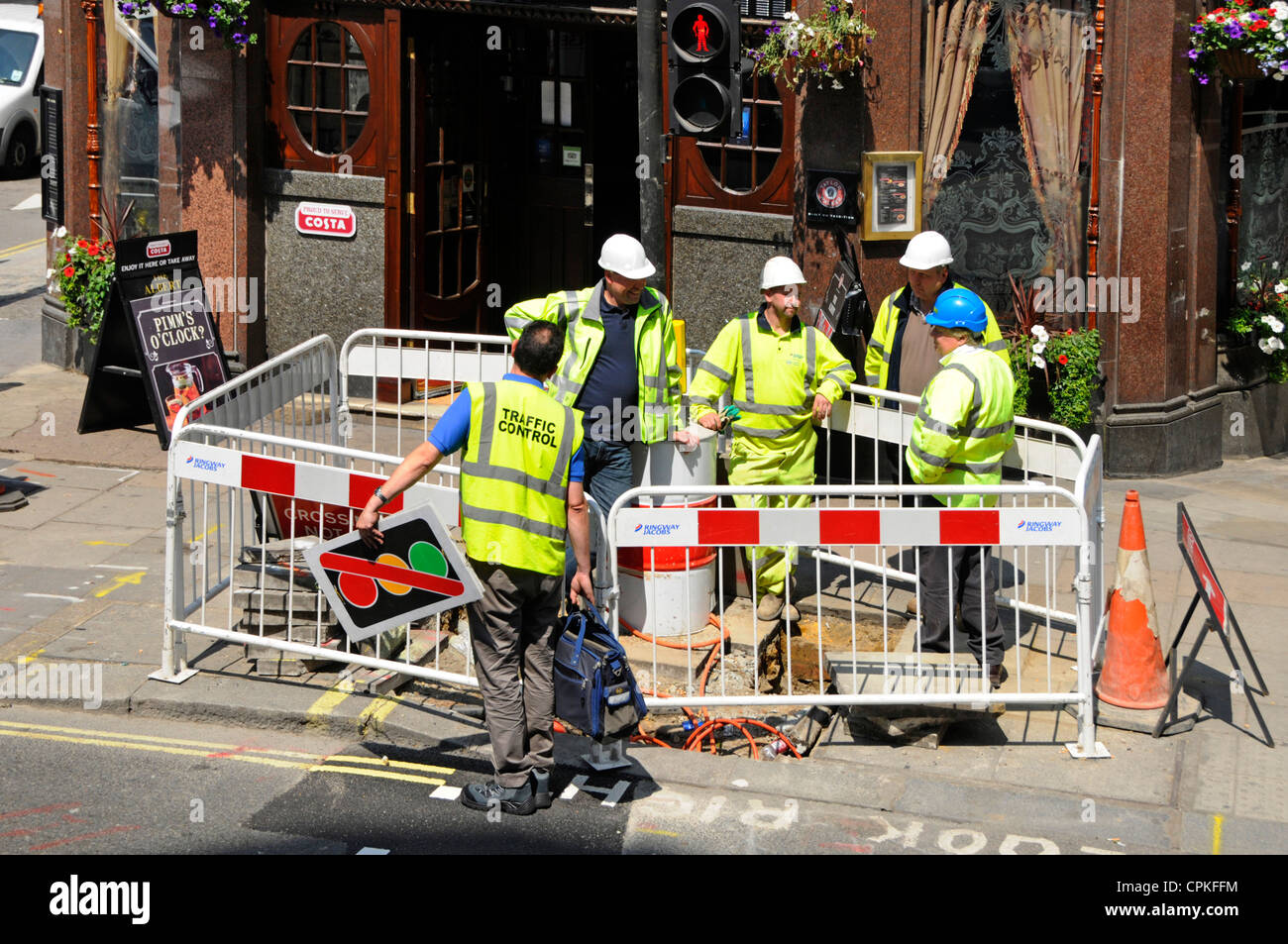 Cinq ouvriers bavarder à côté de trou dans la chaussée Banque D'Images