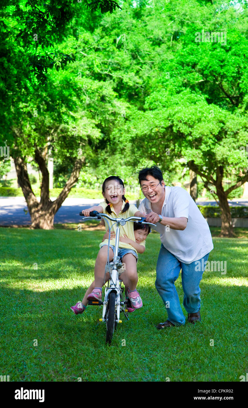L'enseignement du père deux petites filles à faire du vélo Banque D'Images