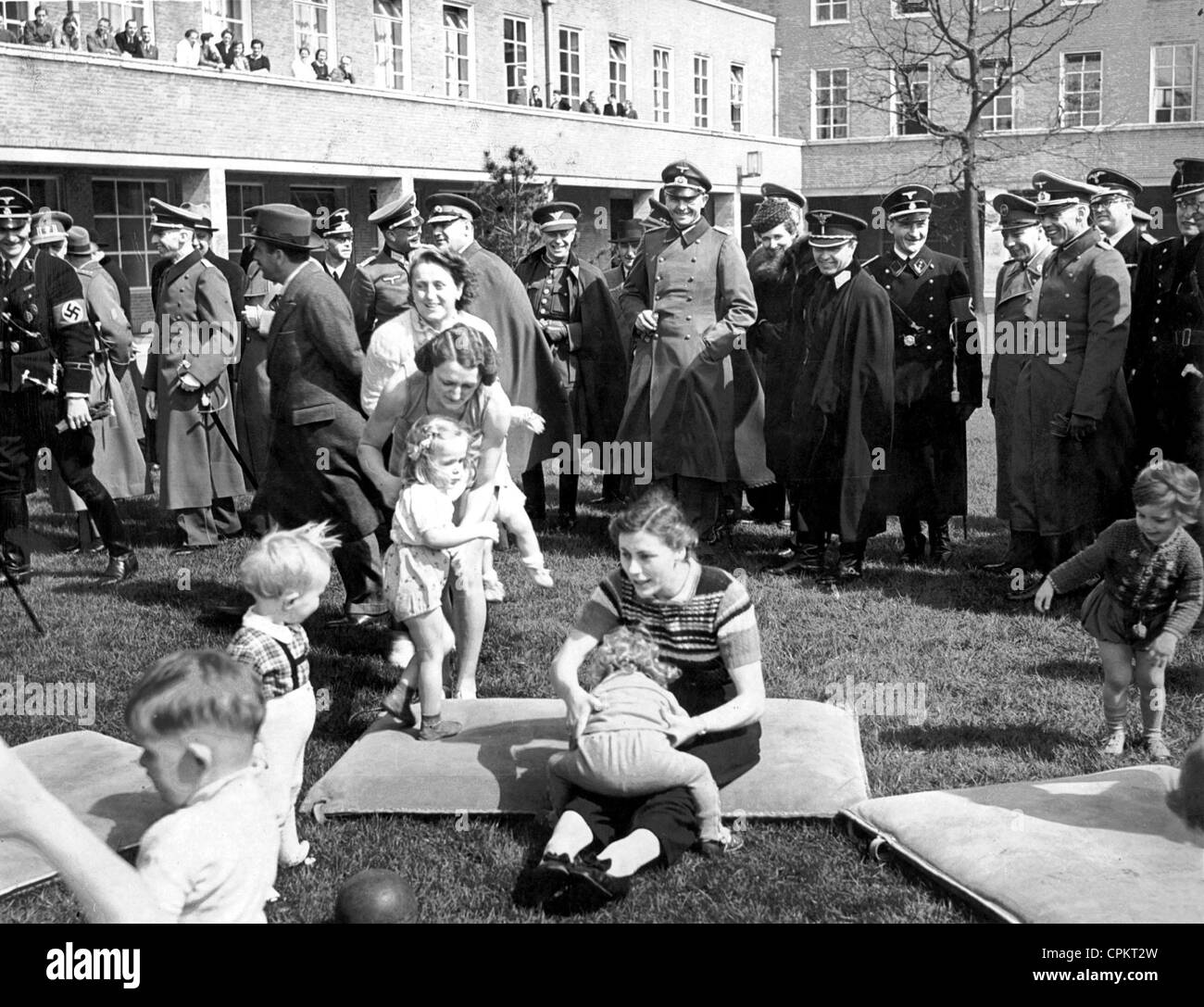 Fonctionnaires et officiers nazis regarder des femmes jouant avec les petits enfants. 1939 Banque D'Images