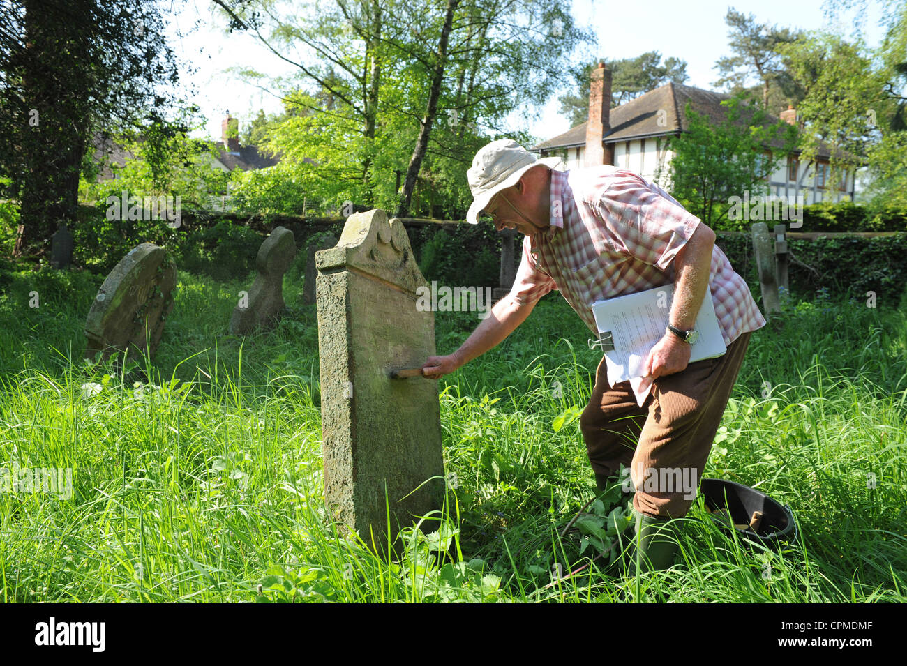 David généalogiste Petley-Jones le nettoyage une pierre tombale au cour de l'église de Worthen Uk Banque D'Images