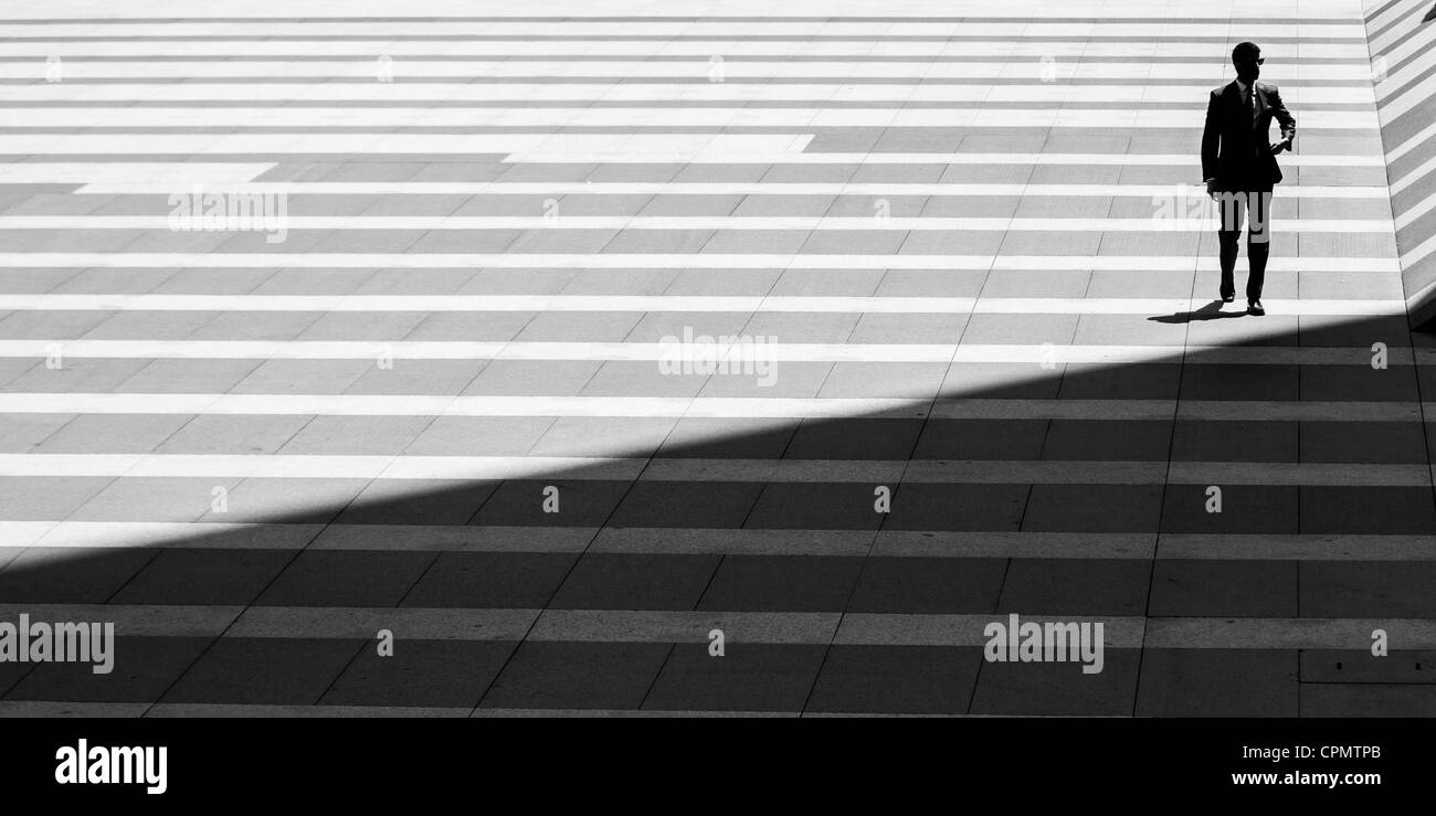 Sur une place de Madrid, la silhouette d'un homme d'affaires éclairé contre un sol carrelé géométrique background Banque D'Images