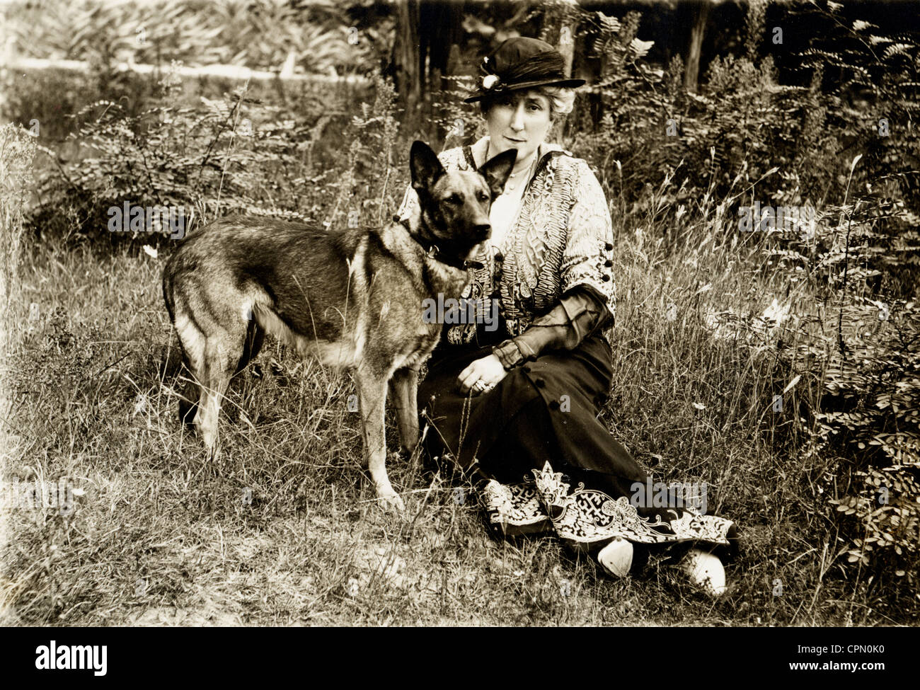 Femme d'âge moyen assis sur le sol avec Berger Allemand Banque D'Images