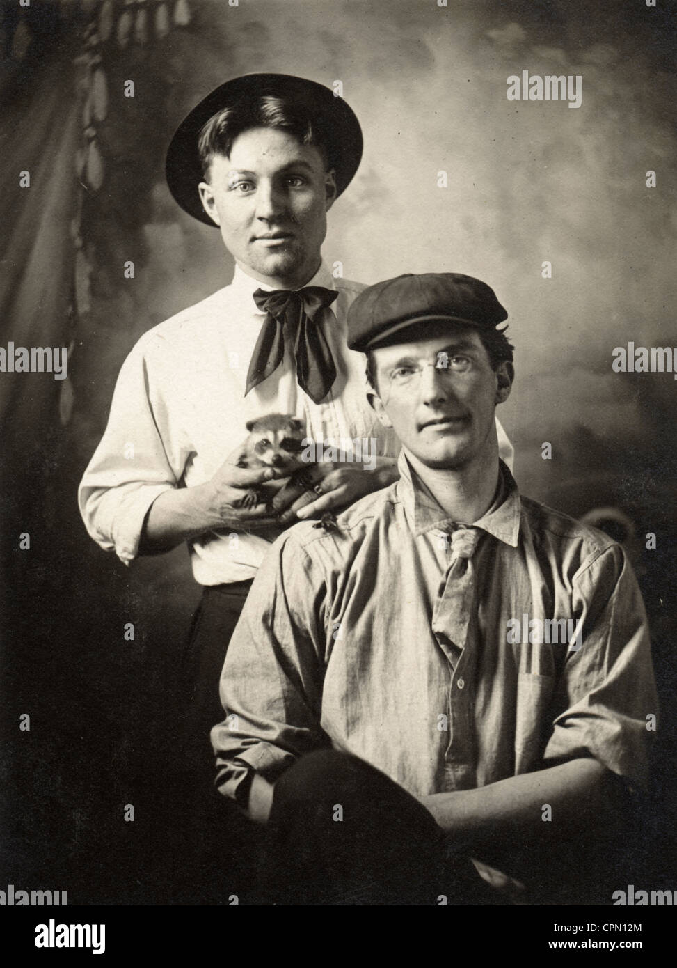 Deux jeunes hommes avec bébé raton laveur Banque D'Images