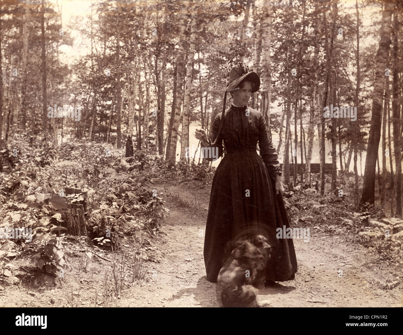 Victorian Woman Taking chien pour une promenade dans les bois Banque D'Images